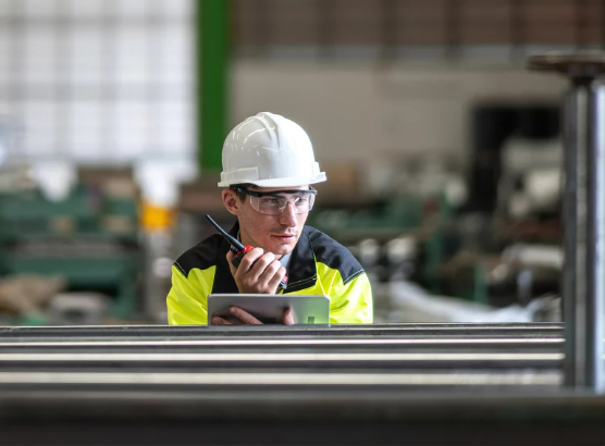 man holding a walkie talkie and tablet standing in a facility